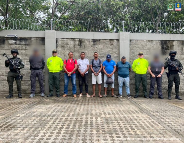 En la fotografía están los procesados de pie con los brazos hacia adelante esposados. Se encuentran acompañados de uniformados del CTI y de la Policía Nacional.