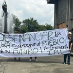 Dos estudiantes sostienen un mensaje alusivo al desfinanciamiento de la Universidad de Antioquia.