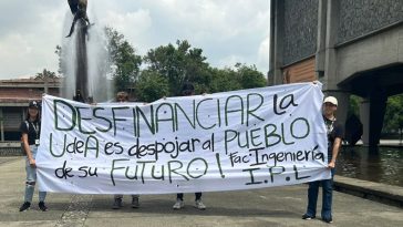 Dos estudiantes sostienen un mensaje alusivo al desfinanciamiento de la Universidad de Antioquia.