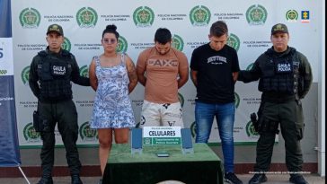 capturados de frente custodiados por dos policías, frente a ellos una mesa con equipo incautado. Detrás de la pancarta de la Policía Nacional.