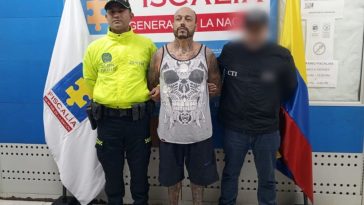 Se observa al capturado de frente en medio de un funcionario de l CTI y otro de Policía Nacional. Atrás, un pendón de Fiscalía General de la Nación