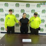 En la fotografía se aprecia de pie y con los brazos atrás a Erika Andrea Varela Pedroza, alias Erika. Viste camiseta y pantalón de color negro. A sus extremos hay uniformados de la Policía Nacional, delante de ellos hay una superficie de color marrón y sobre ella hay un letrero que dice: ‘Orden judicial Concierto para delinquir’. Detrás de ellos hay un pendón institucional de la Policía.