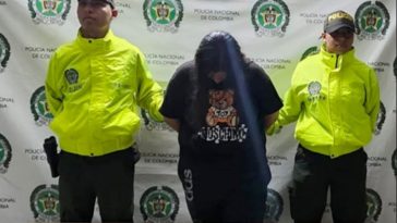 En la fotografía se aprecia de pie, con la cabeza agachada y los brazos atrás a Leidy Johana Osorio Naveros, alias Leidy. Viste con camisa de  manga cortal, de color negro y estampadao en el pecho de colores; así como pantalón negro. A sus extremos hay uniformados de la Policía Nacional. Delante de ellos hay una mesa y sobre ella hay un letrero que dice: ‘Capturada por orden judicial’. Detrás de ellos hay un pendón institucional de la Policía.