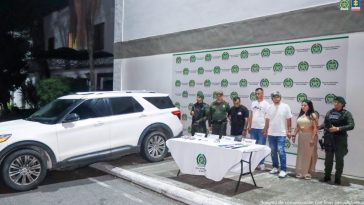 En la imagen se ven cuatro personas detenidas bajo custodia de integrantes de la Policía Nacional. Frente a ellos una mesa con varios elementos incautados. Detrás suyo un backing institucional.