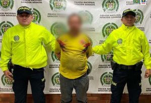 El condenado aparece esposado y custodiado por dos uniformados de la policía nacional.