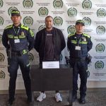 En la fotografía está el procesado en medio de 2 policías y atrás un pendón de la Policía Antioquia