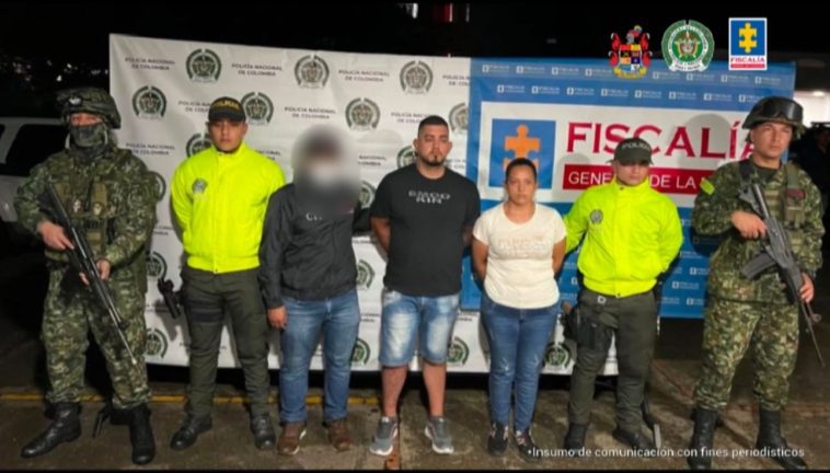 En la fotografía aparecen los capturados junto a un funcionario del CTI, dos uniformados de la Policía Nacional y dos soldados del Ejército. En la parte superior están un banner de la Fiscalía General y otro banner de la Policía