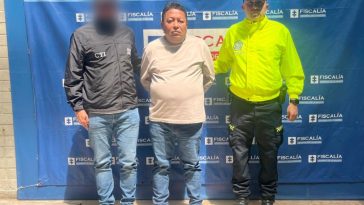  En la imagen se ve el procesado con un servidor del CTI y otro de la Policía Nacional y al fondo un pendón azul de la Fiscalía.