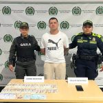 En la imagen está alias Chiki con dos servidoras de la Policía Nacional y adelante una mesa con un celular y dinero incautado