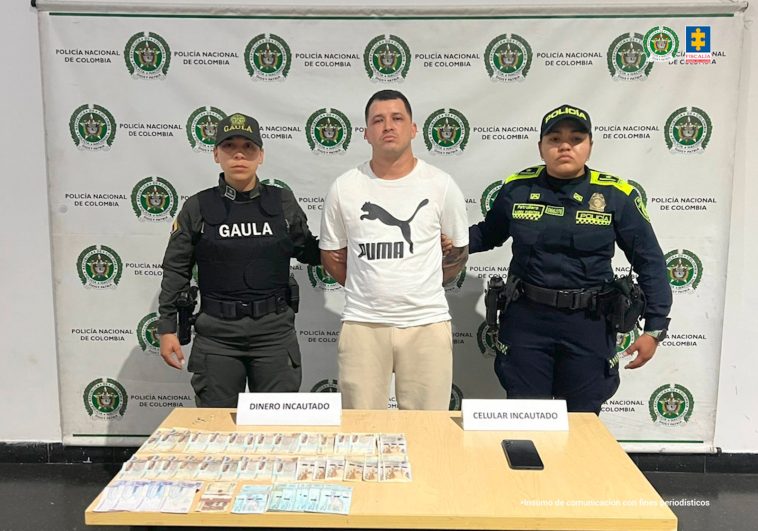 En la imagen está alias Chiki con dos servidoras de la Policía Nacional y adelante una mesa con un celular y dinero incautado