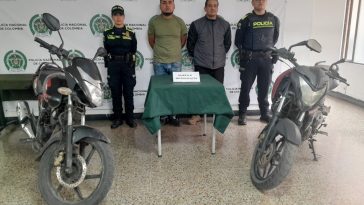 Los capturados aparecen en el centro de la imagen, rodeados de miembros de la policía. A los costados pueden verse dos motocicletas.