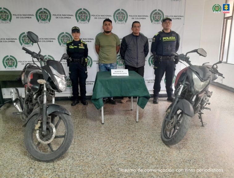 Los capturados aparecen en el centro de la imagen, rodeados de miembros de la policía. A los costados pueden verse dos motocicletas.