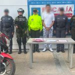 En el centro de la imagen aparece el hombre capturado, frente a él una motocicleta. A ambos costados hay miembros del Ejército, el CTI de la Fiscalía y la Policía. En total 5 personas y el capturado.