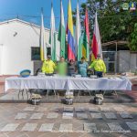 Los capturados se encuentran de frente y custodiados por dos uniformados de la Policía Nacional. En la foto se ve de fondo unas banderas, una mesa con el material incautado. En el piso se observa el estupefaciente incautado durante los registros de allanamientos.