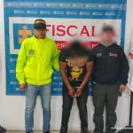 En la fotografía aparece el capturado junto a un funcionario del CTI y un integrante de la Policía Nacional. En la parte superior está un banner de la Fiscalía General.