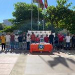 En la fotografía aparecen personas de pie, con los brazos atrás, esposados, custodiados por dos uniformados de la Policía Nacional. Detrás de ellos hay un pendón de esa institución y delante de ellos una mesa con los elementos incautados. 