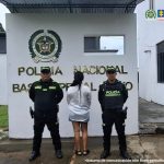 La mujer capturada aparece de espaldas, con dos miembros de la Policía a su lado. Al fondo puede leerse "Policía Nacional".