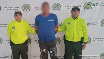 El capturado aparece con sus manos esposadas a la espalda y custodiado por unidades de la Policía Nacional.