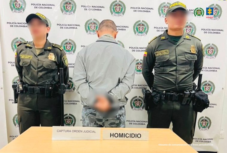 En la imagen está el procesado de espaldas con dos servidores de la Policía Nacional.