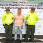 Se visualiza al capturado junto a dos uniformados de la Policía Nacional. Detrás el banner institucional que identifica a la Dirección de Investigación de la Policía Nacional en Norte de Santander 