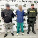 En la imagena aparece el procesado en medio de un servidor del CTI y un patrullero de la policía.