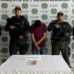 Se visualiza al capturado junto a uniformados del Gaula del Ejército y Policía Nacional. Frente a ellos una mesa con el dinero incautado al momento de la captura. Detrás el banner de la Policía Nacional.