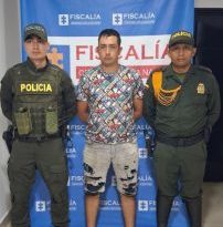 Se observa al capturado junto a dos uniformados de la Policía Nacional. Detrás de ellos el banner que identifica a la Fiscalía General de la Nación.