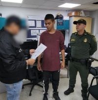 En la fotografía se aprecia de pie, dentro de una oficina a Kevin Eduardo Salcedo Lopera. Viste camiseta de manga corta, de color vinotinto; pantalón de sudadera negro con franja blanca a lo largo, así como zapatillas negras. A la izquierda de él hay un uniformado de la Policía Nacional y a la derecha un servidor del CTI de la Fiscalía quien tiene en sus manos un documento.