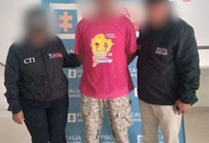 En la imagen aparece una persona detenida, de suéter fucsia, entre dos uniformados del CTI. 