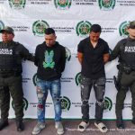 Los capturados se encuentran de  frente y custodiados por dos uniformados del Gaula de la Policía Nacional. 