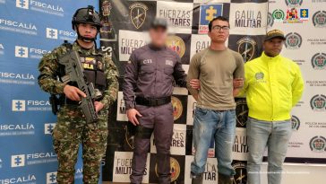 El hombre capturado aparece de pie, con las manos esposadas en la espalda. Está rodeado de miembros de la Policía, el Ejército y el CTI de la Fiscalía.